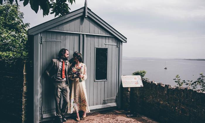 Newly married young couple looking into each other's eyes while leaning against the closed door of the Writing Shed